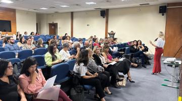 uma pessoa em pé falando e outras sentadas #paratodosverem