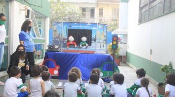 Crianças observam teatro de fantoche sobre trânsito. #paratodosverem