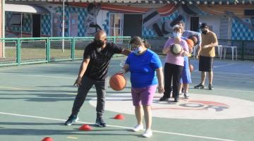 professor está orientando menina que bate bola de basquete. A quadra está com marcações por onde ela tem que ultrapassar. #paratodosverem