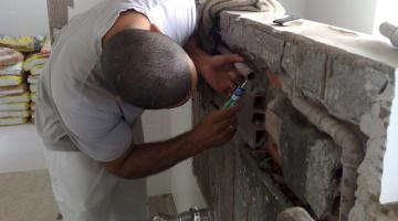 encanador trabalhando em canos dentro de muro. #paratodosverem