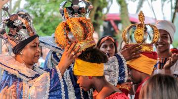 mulher coloca coroa na cabeça de outra #paratodosverem 