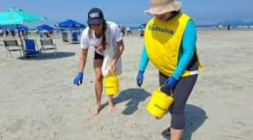 duas pessoas recolhendo lixo na praia #paratodosverem