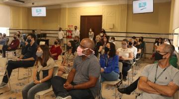 Servidores sentados assistindo apresentação #paratodosverem