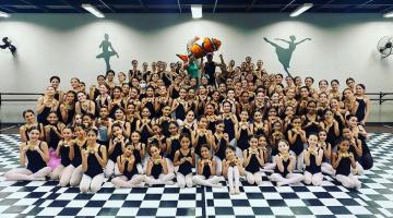 Grande grupo de alunas da escola de bailado posa para foto em sala de dança. #paratodosverem