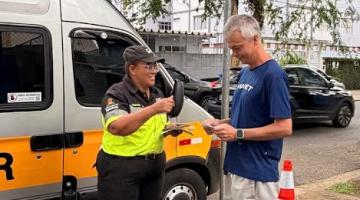 agente entrega panfleto a homem sentado #paratodosverem