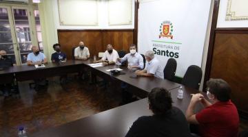 Pessoas conversam sentadas em uma mesa em forma de U #paratodosverem