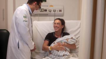 mãe com bebê no colo fala com médico #paratodosverem
