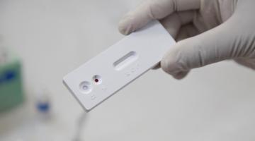 mão com luva segura placa de exame com uma gota de sangue. #Paratodosverem