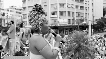 mulher fala ao microfone em comício #paratodosverem