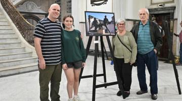 pessoas posam ao lado de fotografia #paratodosverem