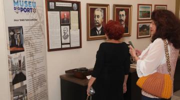 Mulheres observam itens de exposição do Porto de Santos. #pratodosverem