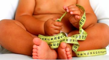 bebê obeso segura fita métrica.  #paratodosverem 