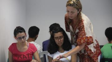 Mulher orienta alunos tocando no piano #paratodosverem