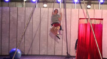 mulher está sentada em balanço de acrobacia de circo. #paratodosverem