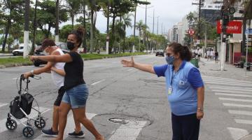 agente da CET estende o braço demonstrando a uma mulher e a um idoso como fazer para atravessar com segurança. #paratodosverem