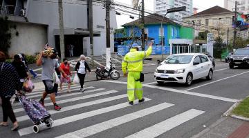 Agente da CET para o trânsito enquanto pedestres atravessam na faixa. #paratodosverem