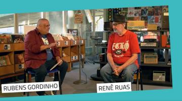 rubens gordinho está sentado ao lado de renê ruas em uma sala de museu. Eles conversam. #paratodosverem