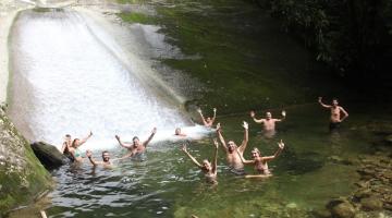 turistas estão na água, logo abaixo de tobogã todos estão com as mãos para cima se divertindo. #paratodosverem