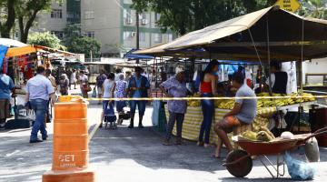 Feira livre armada em rua, com cone delimitando o acesso