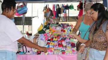 Pessoas olham produto em feira #paratodosverem 
