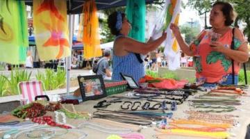 estande de venda com produtos expostos e duas mulheres mexendo em produtos. #paratodosverem