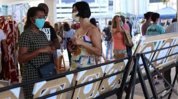 estande de quadros de costas para a foto, com pessoas circulando e conversando. Elas usam máscaras. #paratodosverem