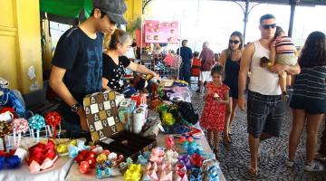 pessoas circulam diante de bancas de artesanato montadas na estação do valongo em Santos. #paratodosverem