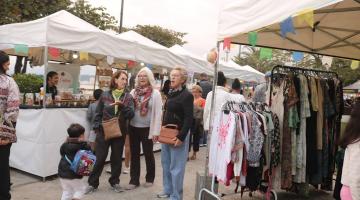 pessoas andando em meio a barracas #paratodosverem