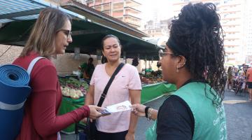 agente distribui panfletos em feira #paratodosverem 