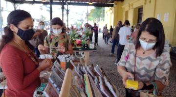 Mulher compra produto em feira #paratodosverem