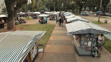 barracas da feirart montadas em praça. Foto pelo alto mostra cobertura idêntica de lona das barracas. #paratodosverem
