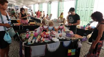 balcão com exposiçõ de artesanato e público em torno,. #paratodosverem