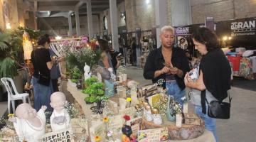 Empreendedora apresenta produto artesanal para cliente em feira. #pratodosverem