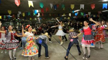 bailarinos dançam quadrilha junina com pessoas assistindo ao fundo #paratodosverem