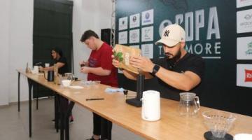 dois homens estão atrás de uma bancada preparando café. #paratodosverem 