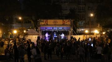 Público confere apresentação de banda, à noite, em palco montado na Praça Mauá. #pratodosverem