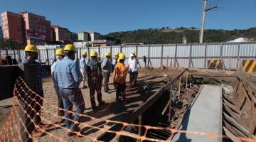 várias pessoas usando capacete estão olhando andamento de obra. #paratodosverem