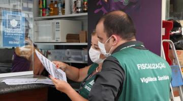 Fiscais observam documentação de comércio. #pracegover