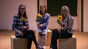 em cena de flores invisiveis, 3 mulheres seguram flores