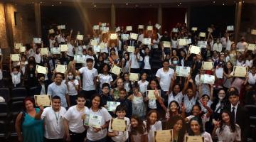 alunos estão na plateia de teatro ostentando certificados. #paratodosverem