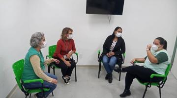 Quatro mulher conversam em uma sala sentadas em cadeiras. #paratodosverem