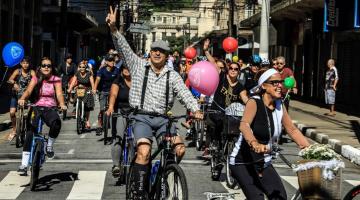 pessoas caracterizas passeiam de bicicleta em rua #paratodosverem