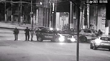 viaturas da polícia e da guarda em rua. Há pessoas se movimentando. é noite. #paratodosverem 