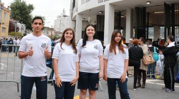 quatro alunos com camisas do santos posam na porta do estádio #pracegover