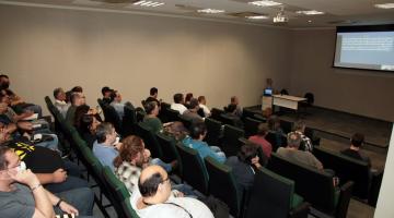 pessoas sentadas em auditório observando telão #paratodosverem