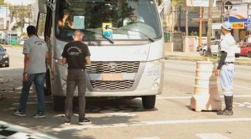 micro-ônibus está parado em avenida e três fiscais estão à frente. Eles são da Seectur, Artesp e CET-Santos 