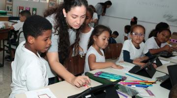 professora mostra tabtlet para aluno #paratodosverem 