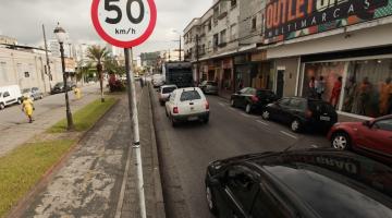 Placa de velocidade de 50km e ao lado via com carros. #paratodosverem