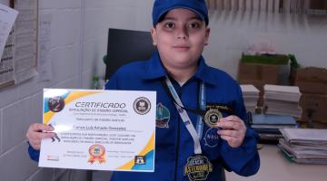 Aluno mostra seu certificado internacional. #Paratodosverem.