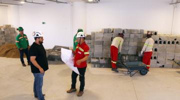 dois homens seguram plangta de construção. #paratodosverem 